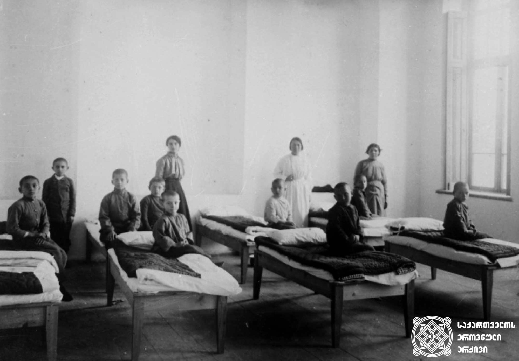 სოხუმის  სასწავლებელთან  არსებული  თავშესაფარი; სკოლის გამგე, მომვლელები და ბავშვები <br>
1916  წელი <br>
The shelter near the Sokhumi school: the school administrator, caretakers and children<br>
1916