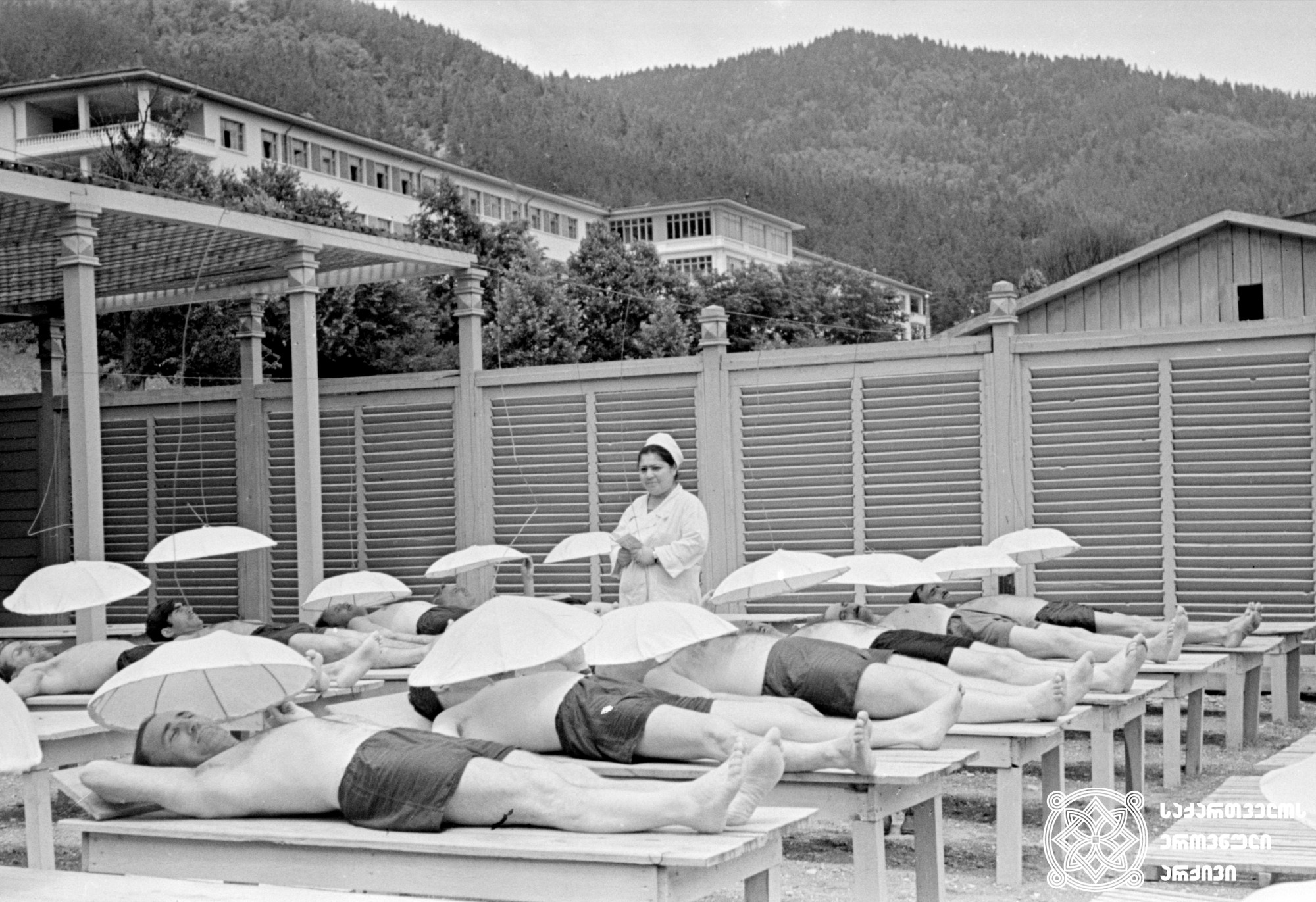 დამსვენებლები პროცედურის დროს. სანატორიუმი „ლიკანი“, ბორჯომის მუნიციპალიტეტი, 1964 წელი. <br>
The vacationers during the procedure. The Sanatorium "Likani", Borjomi Municipality, 1964.