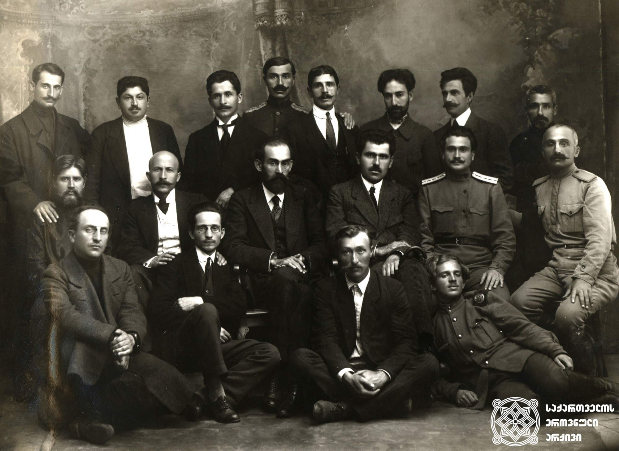 სოხუმელი სოციალ-დემოკრატების ჯგუფი. ცენტრში: მარცხნივ - ბენია ჩხიკვიშვილი, მარჯვნივ - იოანის ფაშალიდისი. <br>
1918 წელი. <br>
Group of Social Democrats from Sokhumi. In the center: on the left – Benia Chkhikvishvili, on the right - Ioannis Passalidis. <br>
1918.