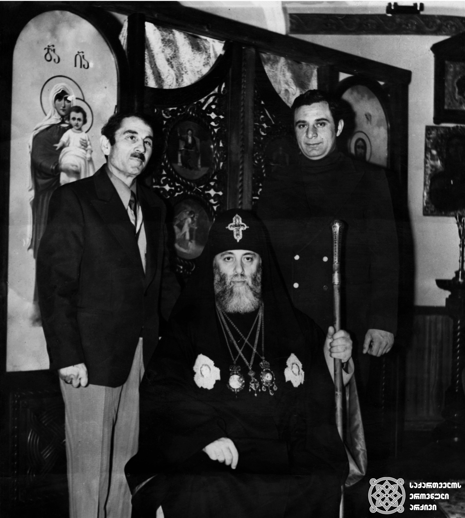 ზის: ილია II სრულიად საქართველოს კათოლიკოს-პატრიარქი, მარჯვნივ: ვიქტორ შიოლაშვილი, პატრიარქის ძმა (შემდეგში ბერი გიორგი), მარცხნივ: გივი ბადაშვილი. <br>
1978 წელი <br>
Ilia II, Catholicos-Patriarch of All Georgia sitting; On the right: Viktor Shiolashvili, the Patriarch’s brother (later Monk Giorgi); On the left: Givi Badashvili. <br>
1978