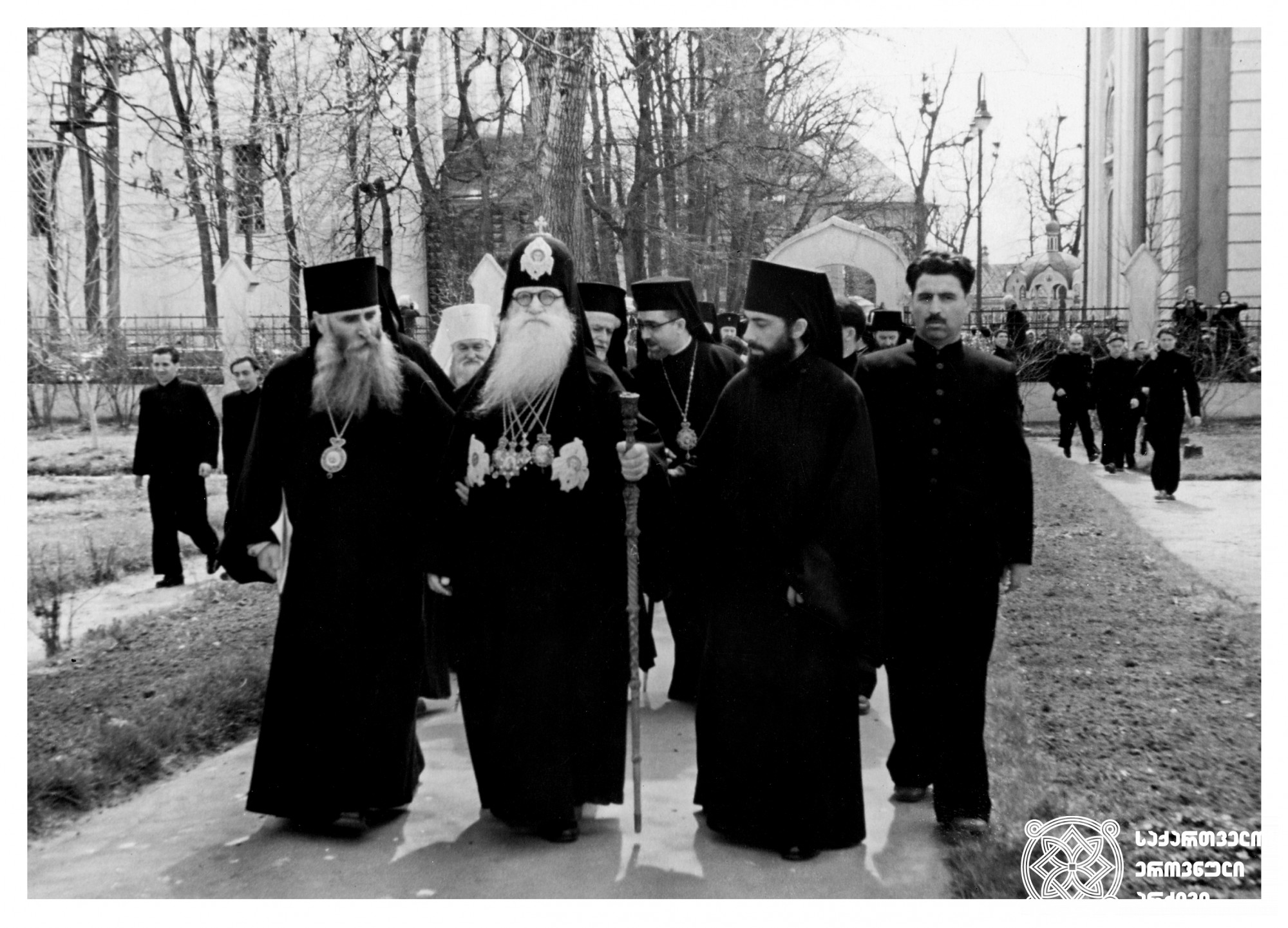 სრულიად საქართველოს კათოლიკოს-პატრიარქ მელქისედეკის (ფხალაძე) სტუმრობა ზაგორსკში <br>
ფოტოზე წარმოდგენილია ერთ მოქმედი და ორი მომავალი პატრიარქი: სრულიად საქართველოს კათოლიკოს-პატრიარქი მელქისედეკ III (ფხალაძე), მისგან მარცხნივ ეპისკოპოსი დავითი (დევდარიანი, მომავალში კათოლიკოს-პატრიარქი დავით V), მარცხნივ - ბერი ილია (შიოლაშვილი, მომავალში კათოლიკოს-პატრიარქი ილია II)<br>
1957 წელი <br>
The Visit of Melchisedek, Catholicos-Patriarch of All Georgia, to Zagorsk The photo features one current and two future Patriarchs: Melchisedek III, Catholicos-Patriarch of All Georgia; to his left, Bishop Davit (Devdariani, the future Catholicos-Patriarch Davit V); and on the left —Monk Ilia (Shiolashvili, the future Catholicos-Patriarch Ilia II) <br>
1957