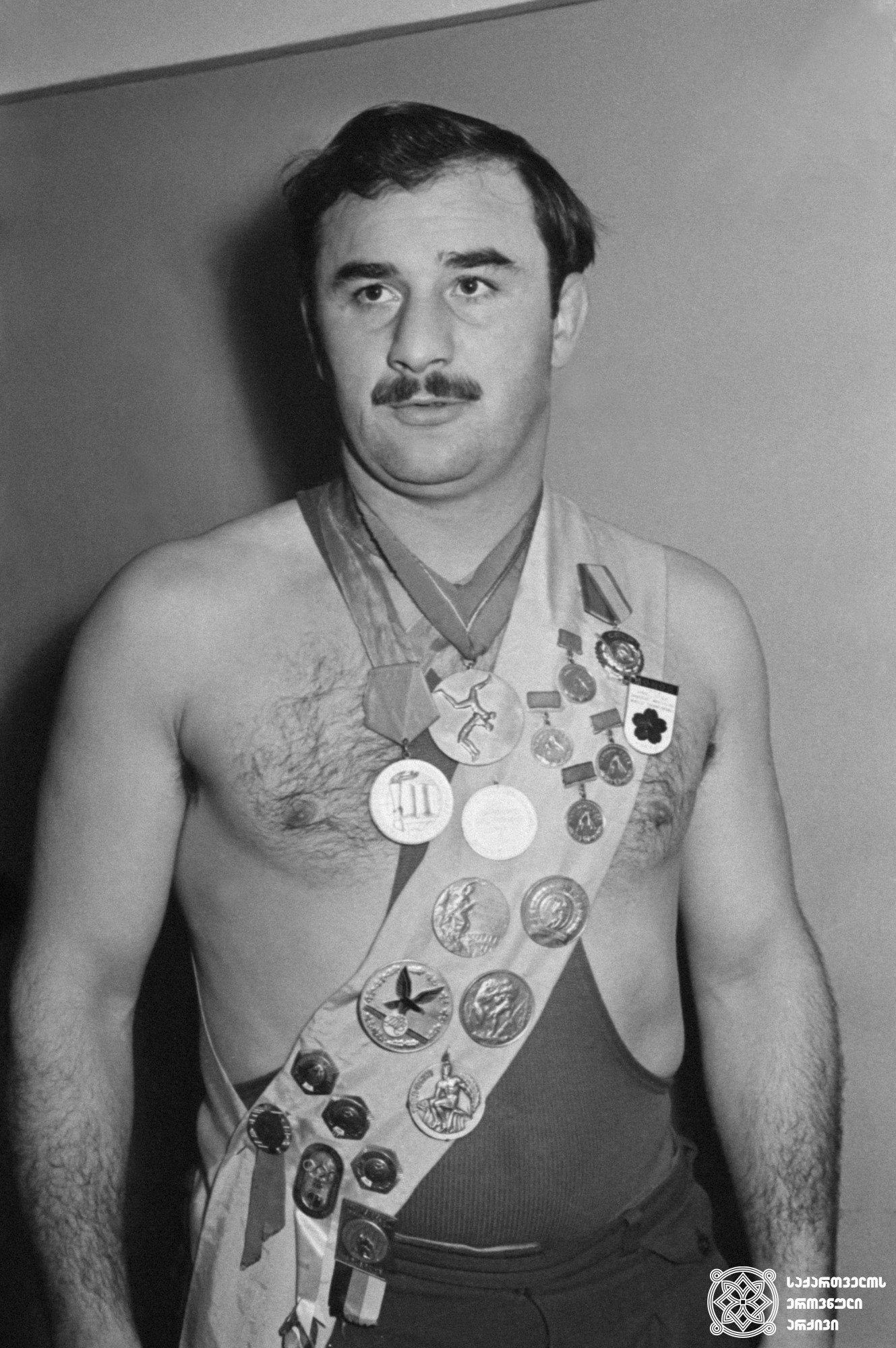 გივი კარტოზია. <br>
გივი კიკვაძის ფოტო, 1959 წელი. <br>
XVI ოლიმპიური თამაშების ჩემპიონი ბერძნულ-რომაულ ჭიდაობაში (1956 წელი; მელბურნი); XVII ოლიმპიური თამაშების მესამე პრიზიორი (1960 წელი, რომი). <br>
Givi Kartozia. <br>
Photo by Givi Kikvadze, 1959. <br>
Champion of the XVI Olympic Games in Greco-Roman style Wrestling (1959, Melbourne); third-prize winner of the XVII Olympic Games (1960, Rome).