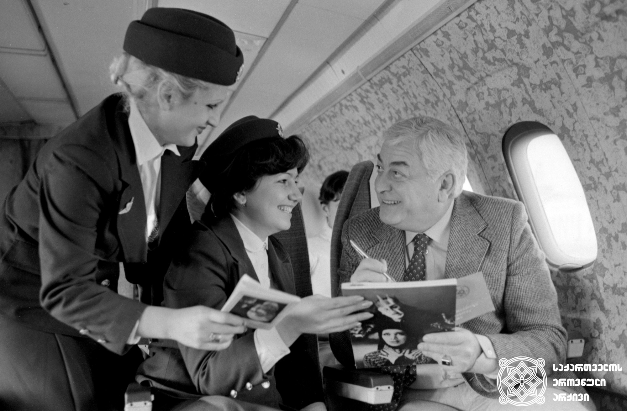 რამაზ ჩხიკვაძე ბორტგამცილებლებს აძლევს ავტოგრაფს. <br>
ანატოლი რუხაძის ფოტო. <br>
1983 წელი. <br>
Ramaz Chkhikvadze signs an autograph to stewardess. <br>
Photo by Anatoly Rukhadze. <br>
1983. <br>